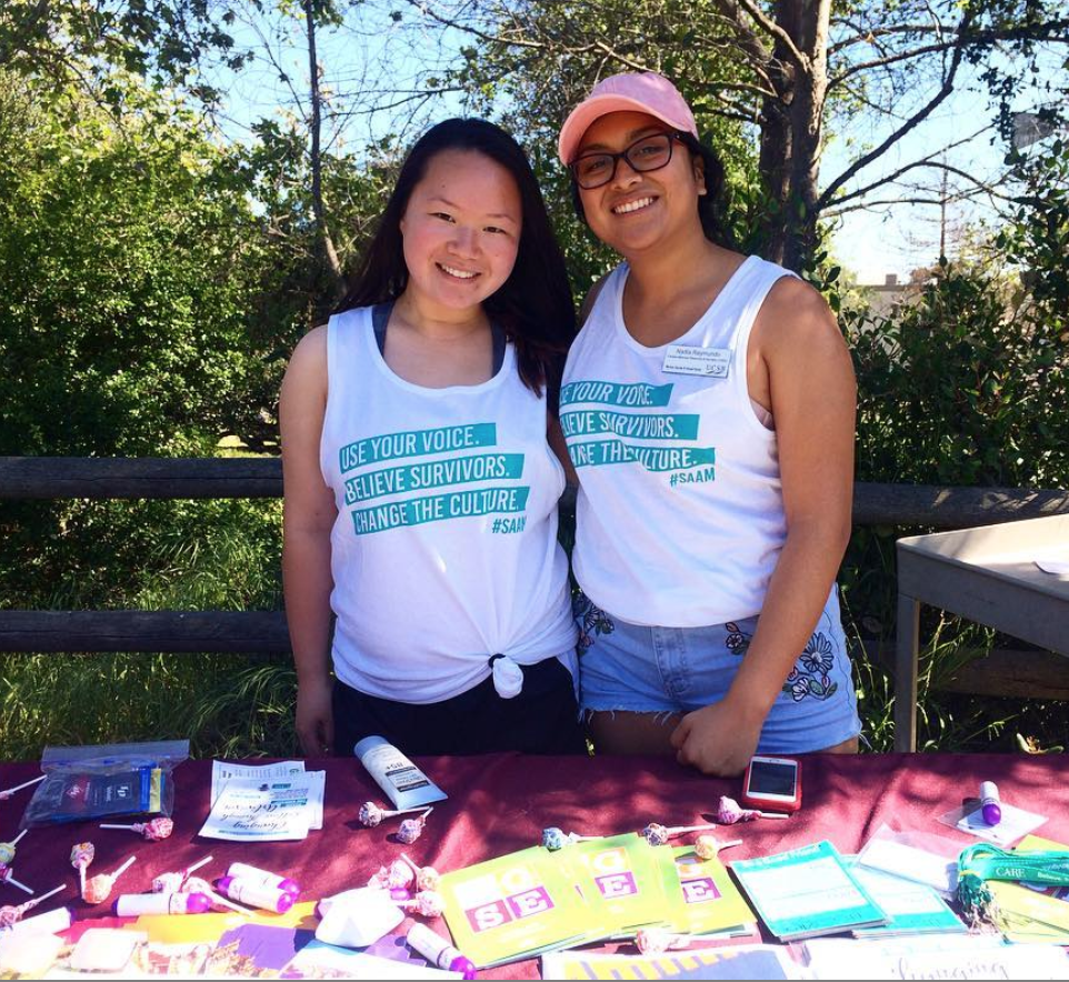 Two students tabling and wearing shirts that say "Use your voice. Believe Survivors. Change the Culture. #SAAM
