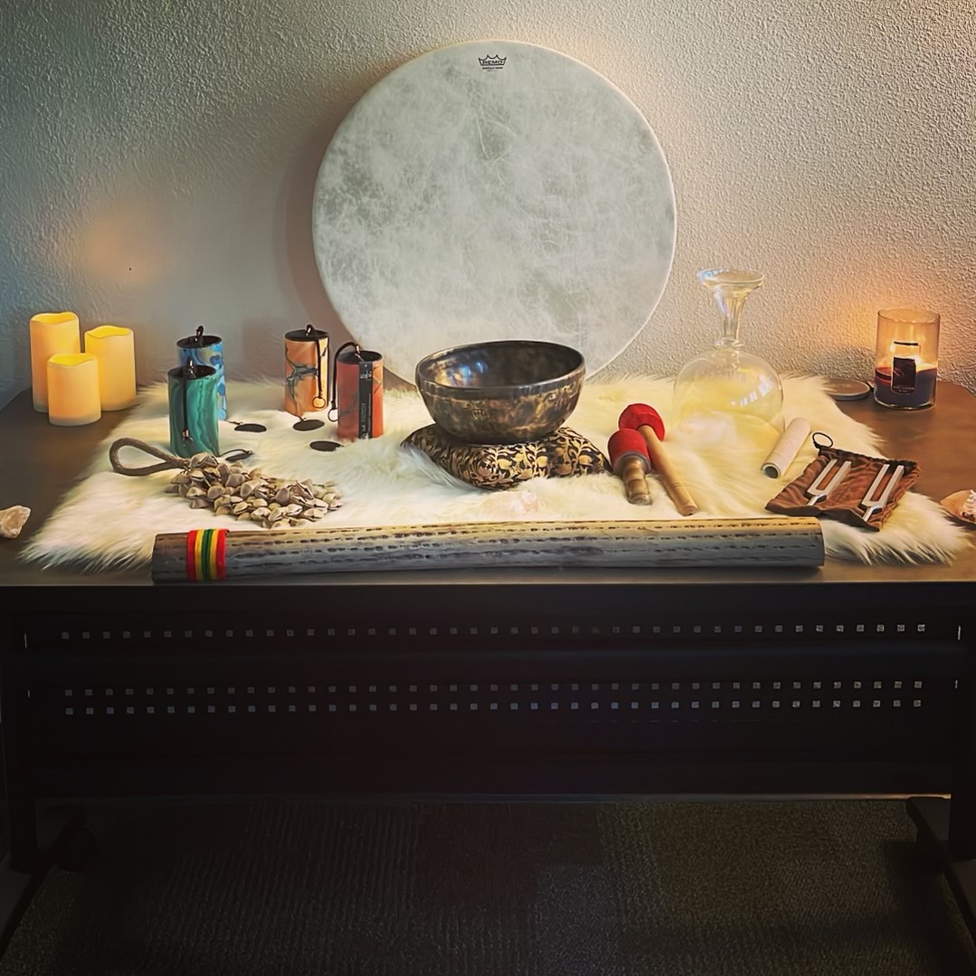 Sound healing instruments laying on a mat with surrounded by candles.