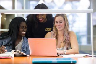 Three students looking at a laptop screen Three students looking at a laptop screen