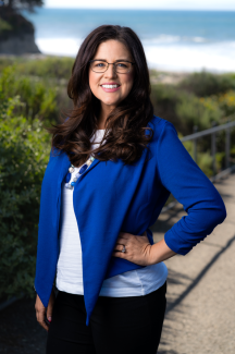 Briana Miller Headshot standing in front of greenery and the ocean 