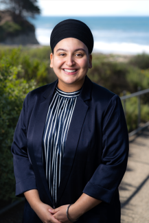 Harleen Kaur Jassal Headshot standing in front of greenery and the ocean