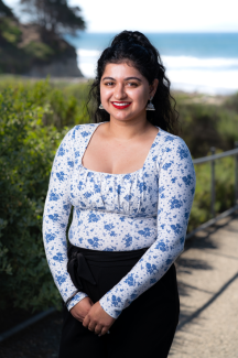 Manpreet Kaur Headshot standing in front of greenery and the ocean 