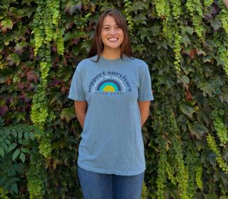 Noellani standing in front of greenery wearing a blue shirt.